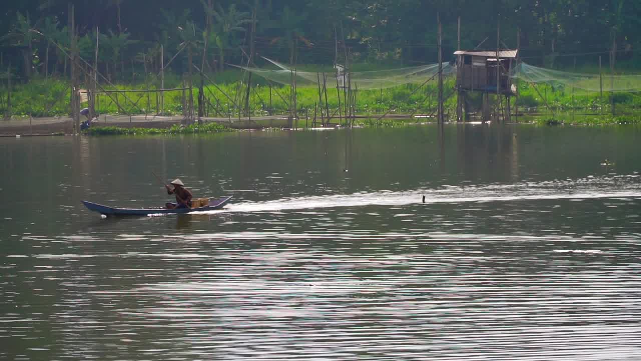 Premium stock video - Fisherman is crossing lake with traditional boat ...