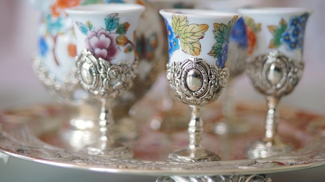 Close-up of Ornate Porcelain Cups with Silver Holders on a Decorative Tray