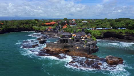 las olas del océano se estrellan en la isla rocosa con tanah lot, templo tradicional balinés en bali, indonesia