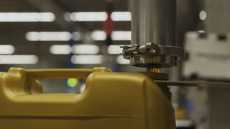 a machine depositing oil into a golden plastic jug