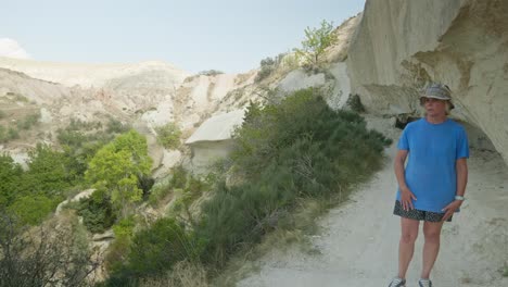 una excursionista nerviosa en el estrecho y empinado sendero rocoso del valle rojo de capadocia