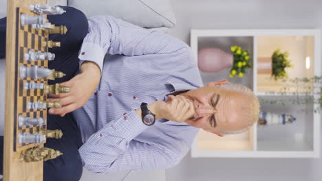 Vertical-video-of-The-old-man-is-home-alone-and-playing-chess.