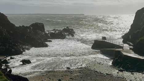 Silberne-Sturmwellen-Brechen-Auf-Die-Felsen-In-Der-Badebucht-In-Der-Nähe-Von-Tramore,-IRL