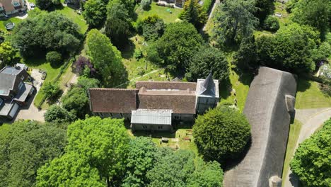 Eine-Dorfkirche,-Aufgenommen-Von-Einer-Drohne,-Die-Langsam-über-Die-Spitze-Fliegt-Und-Das-Orangefarbene-Ziegeldach-Zeigt