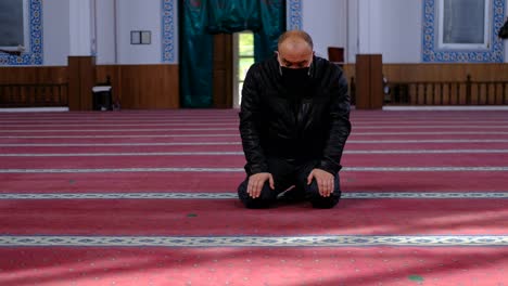 man wears mask and turns his head in mosque