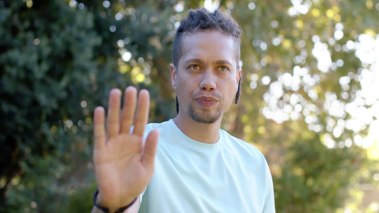 African American man checking smartwatch and gesturing to camera in front yard, responding to music