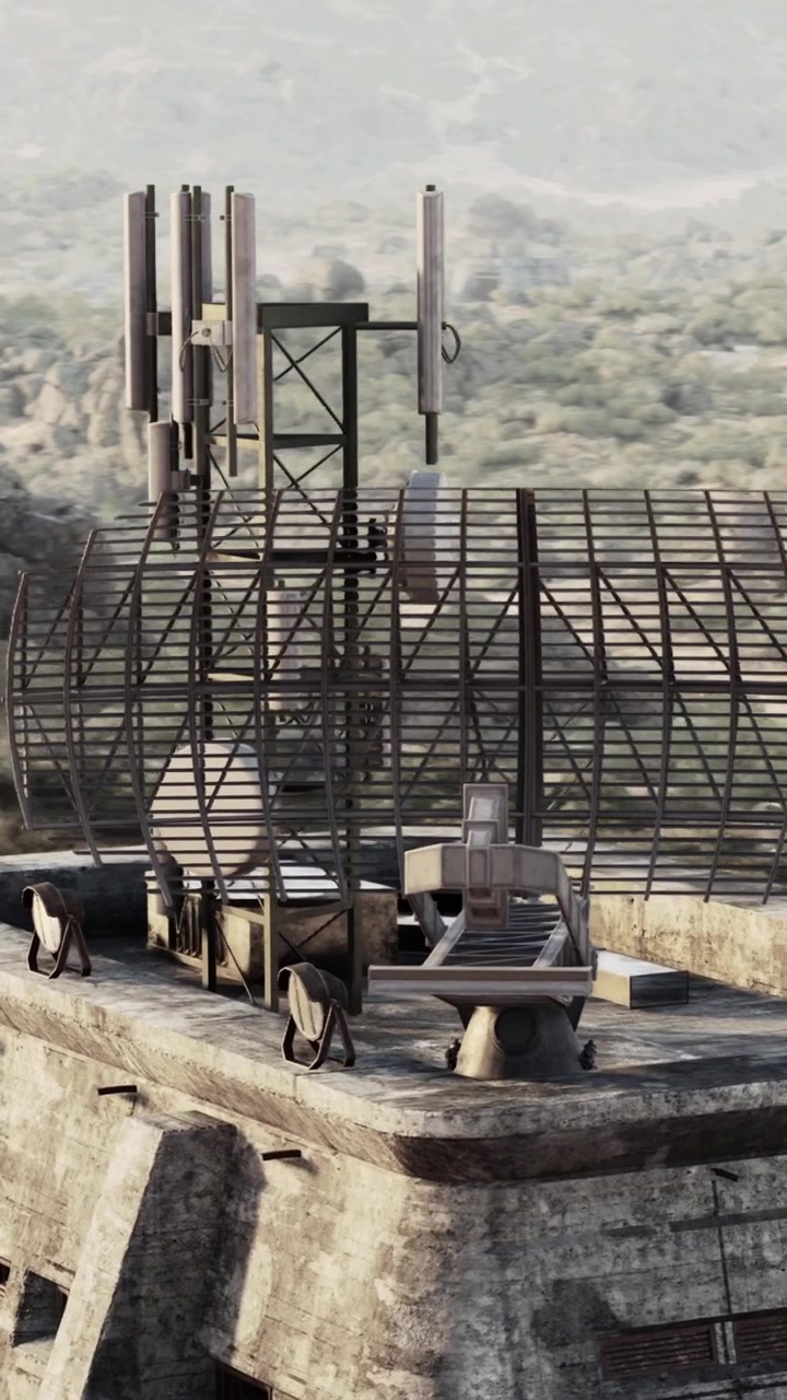 Torre de sinal em uma antiga instalação cercada por montanhas e árvores.