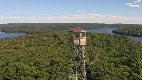 drone reversing away from tall fire tower beside lakes in ontario canada,