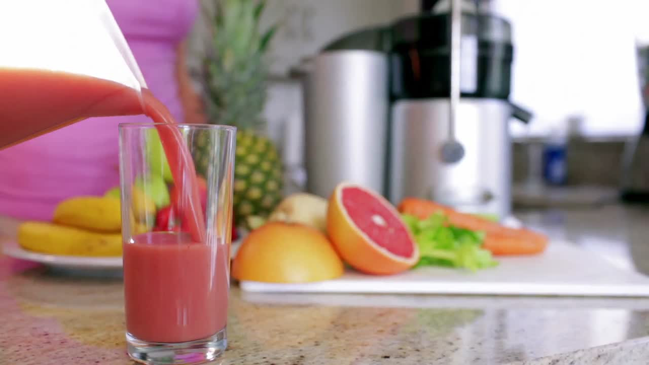 Kvinne som heller fersk frukt- og grønnsaksjuice