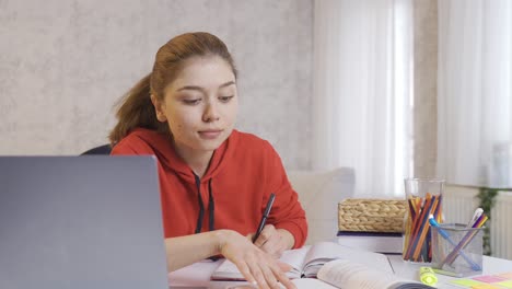 una estudiante universitaria estudiando felizmente en casa.