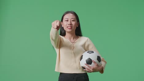 woman holding soccer ball and pointing