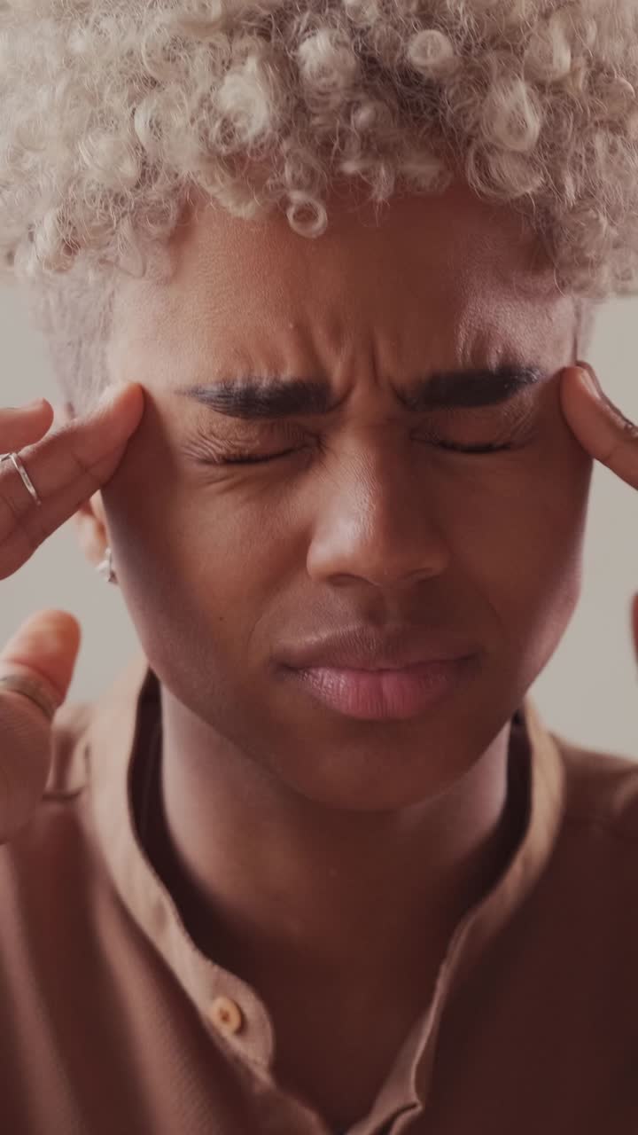 Young african american woman massages temples due to another migraine attack