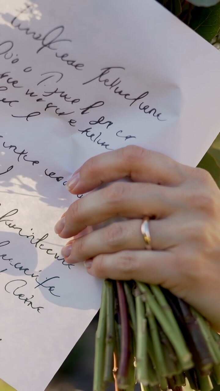 Vertical video: Hand entering frame adjusting written note in sunny garden to steady bouquet stems