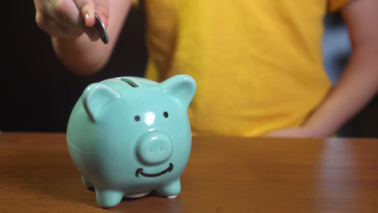 un niño poniendo monedas en una alcancía.