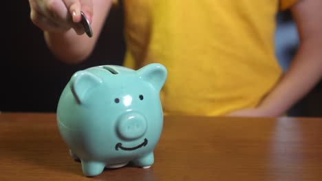 un niño poniendo monedas en una alcancía.