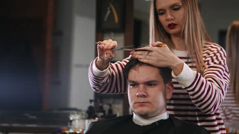 Female-hairdresser-cutting-hair-of-smiling-man-client-at-beauty-parlour