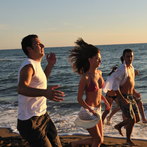 friends running and walking on the beach at sunset