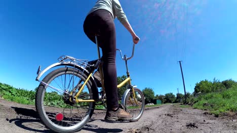 young woman riding vintage bicycle along a rural road in a village