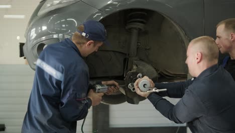 team of mechanics repairing car suspension