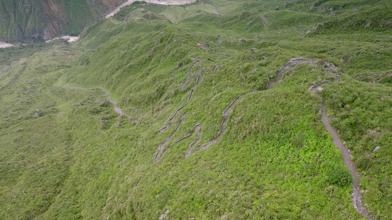 Drone shot following the trekking path from Cabanaconde to the Oasis of Sangalle, capturing hikers making their way down through the breathtaking Colca Canyon landscape.