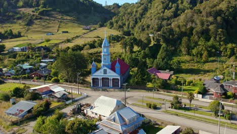 Tenaun-Dorf-Mit-Ikonischer-Blauer-UNESCO-Weltkulturerbe-Kirche-In-Chiloé,-Sonniger-Tag,-Luftaufnahme