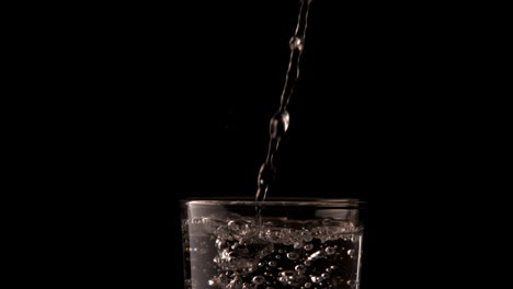 water pouring into glass on black background