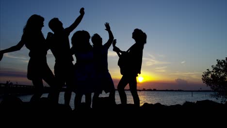 silhouette of friends enjoying sunset on beach vacation