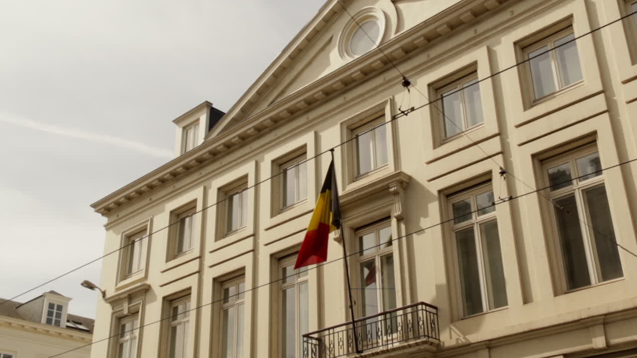 Belgian flag flying and blowing in the wind in the sky on top fo a building in brussels