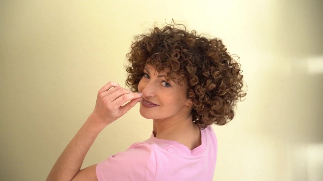 Rear view of female model playing with her hands in her curly afro hair
