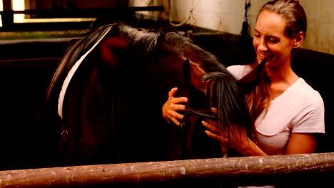 woman stroking horse in stable 4k