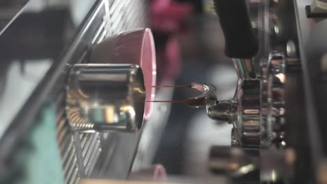 Vertical,-slow-drip-coffee-comes-out-of-dual-pipes-in-shiny-silver-machine