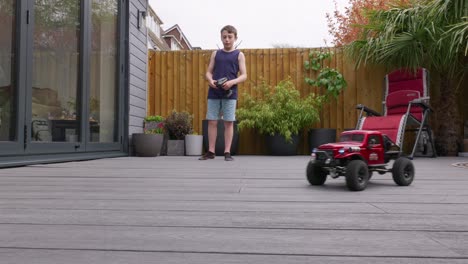 young boy at home outdoors in the garden playing with his rc car, truck, 4 x 4