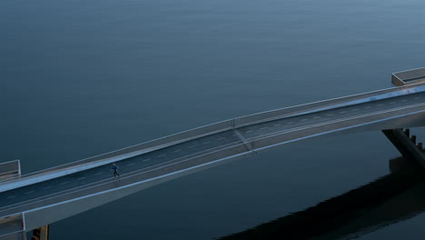 drone shot of a man running across a bicycle bridge over the canals one early morning in copenhagen