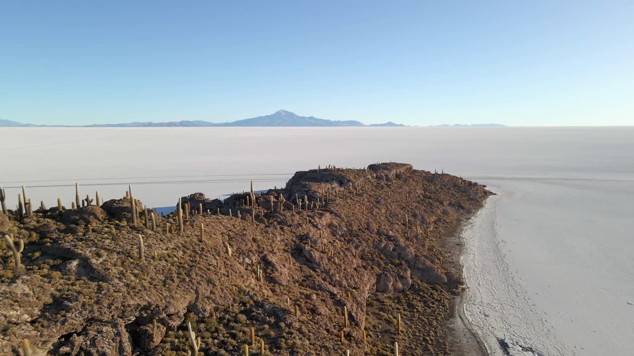 Drone dolly over rocky terrain of Isla Incahuasi surrounded by vast white salt flat