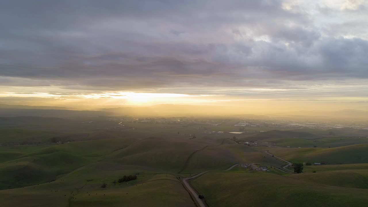 Reverse Dolly of Moody Clouds at Sunset and Winding Road Passing Through Rolling Hills