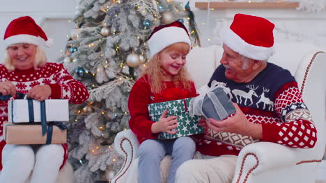 Nieta-Intercambiando-Cajas-De-Regalo-De-Navidad-Con-Un-Abuelo-Mayor-Feliz-Y-Asombrado-En-Casa