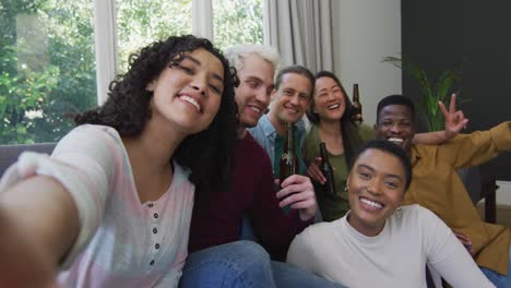 Diverse-group-of-happy-male-and-female-friends-smiling-and-taking-selfie-in-living-room