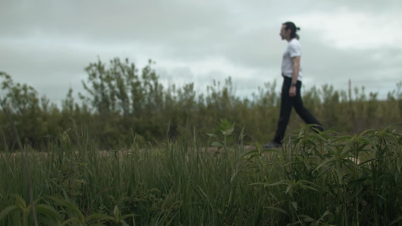 Man walking alone on dirt road by expansive fields