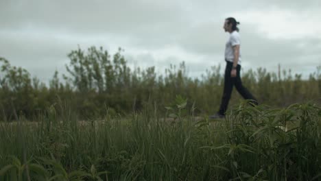 man walking alone on dirt road by expansive fields