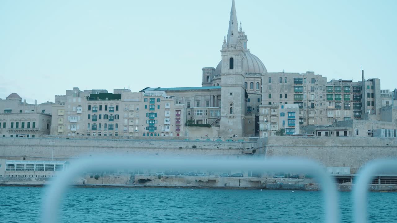 Static view of Valletta’s limestone skyline in Malta, featuring historic buildings, colorful balconies and a prominent dome under soft daylight