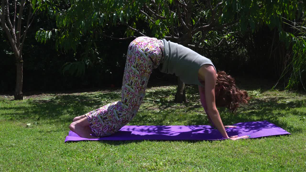 Young redhead woman practicing yoga in her garden