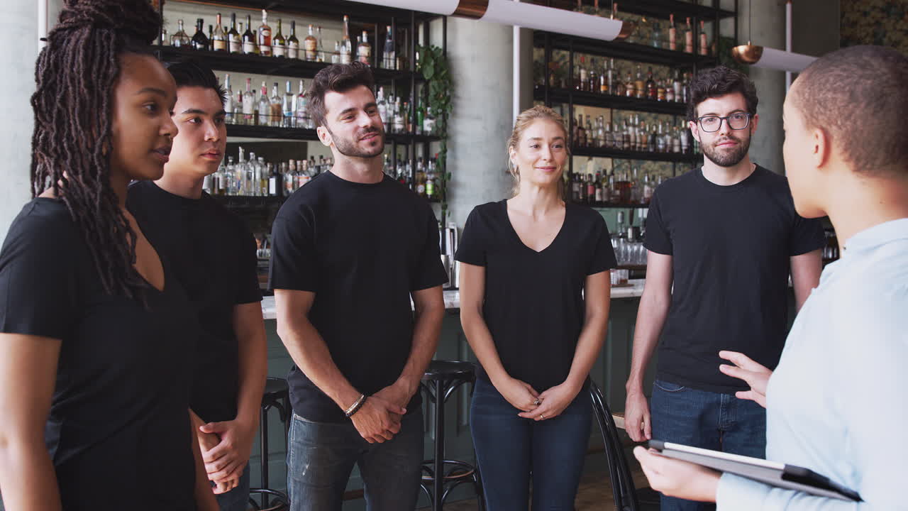 gerente de restaurante femenino con tableta digital dando al equipo hablar con el personal de espera