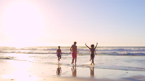 friends running on beach at sunset