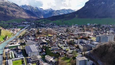 Swiss-City-with-buildings-and-homes-during-sunny-day-with-snowy-mountains-in-background