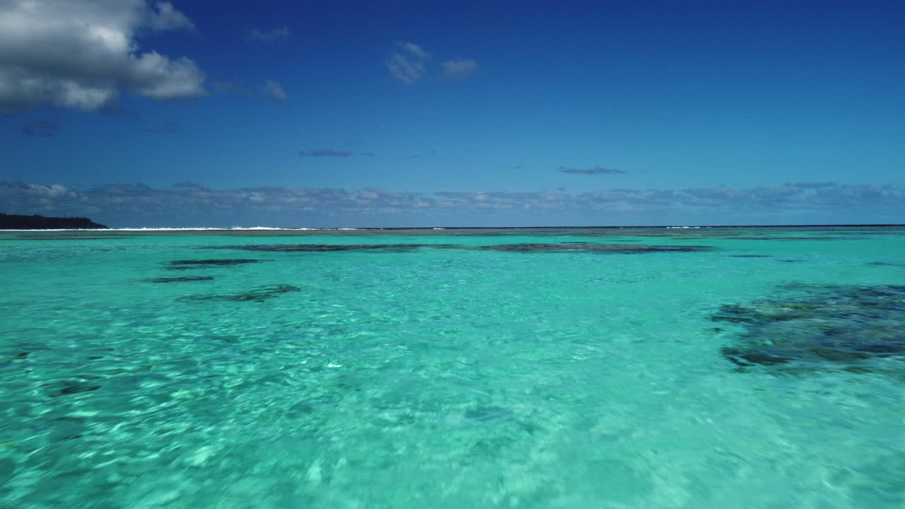 Low flyover above clear shallows and coral reef near Mare Island in New Caledonia