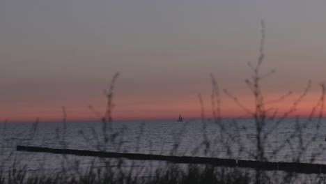 a sailboat sailing at the horizon at the baltic sea while sunset at