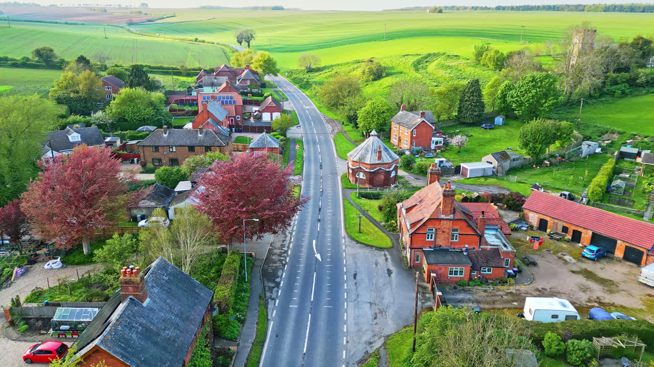 Aerial drone view of Burwell village, previously a medieval market town, showcases countryside fields, aged red brick houses, and the disused Saint Michael parish church on Lincolnshire's Wold Hills