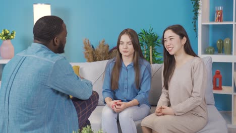 african teenager chatting with young asian and european women at home. they are happy and fun.