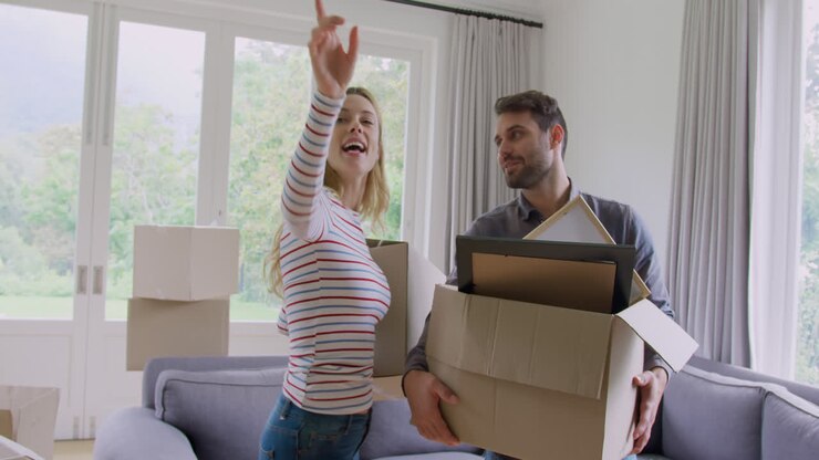 Couple holding cardboard boxes and interacting with each other in new home 4k