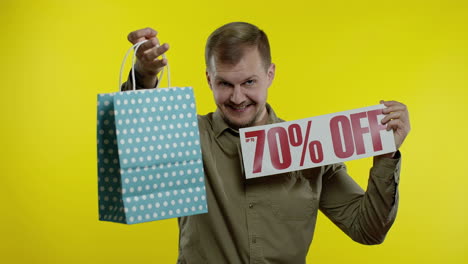 man showing up to 70 percent off inscription and shopping bag, looking satisfied with low prices